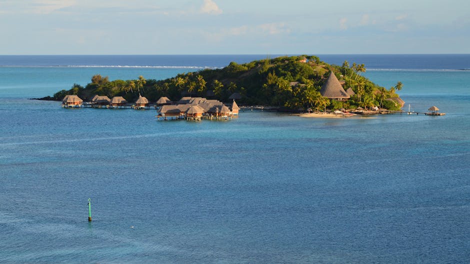Scenic view of a tropical island with overwater bungalows in clear blue waters.