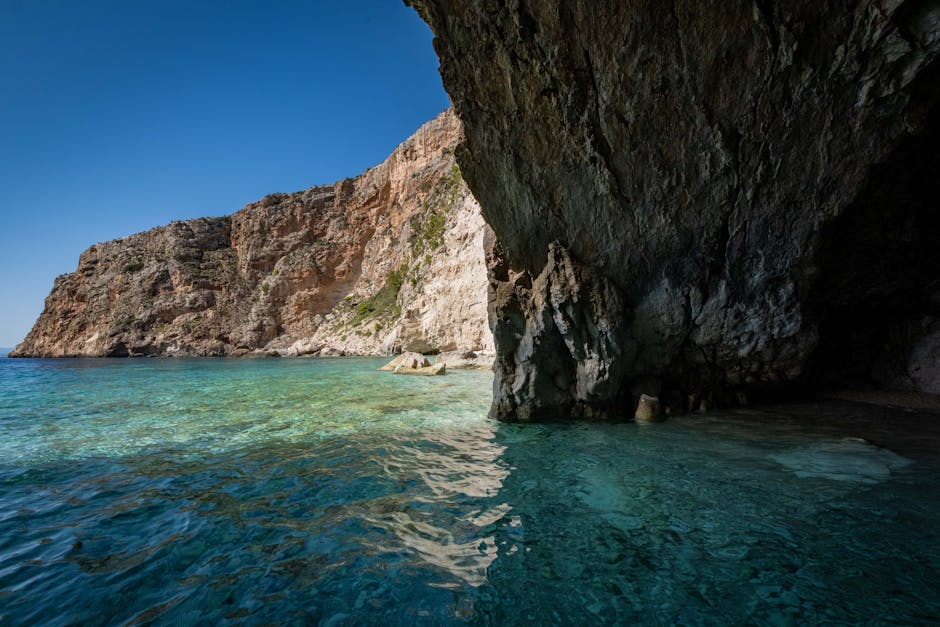 Majestic coastal cliff with azure waters under a bright, clear sky.